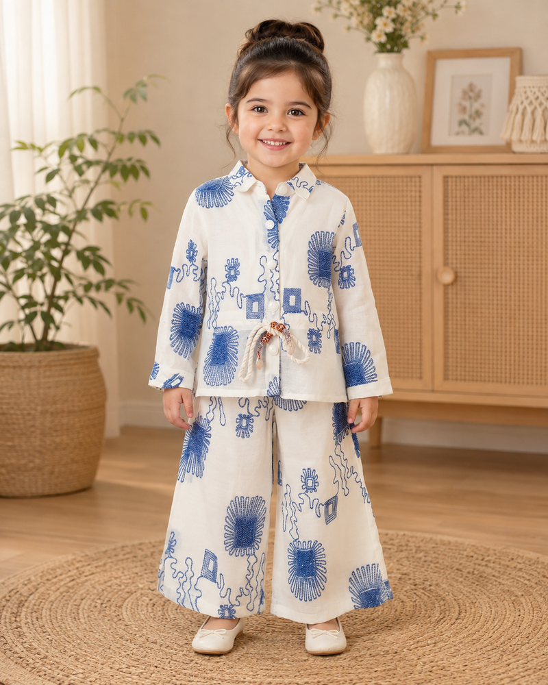 Girl wearing a white and blue floral printed full sleeve top with matching wide-leg pants co-ord set by Kidaura.
