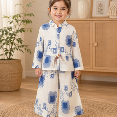 Girl wearing a white and blue floral printed full sleeve top with matching wide-leg pants co-ord set by Kidaura.